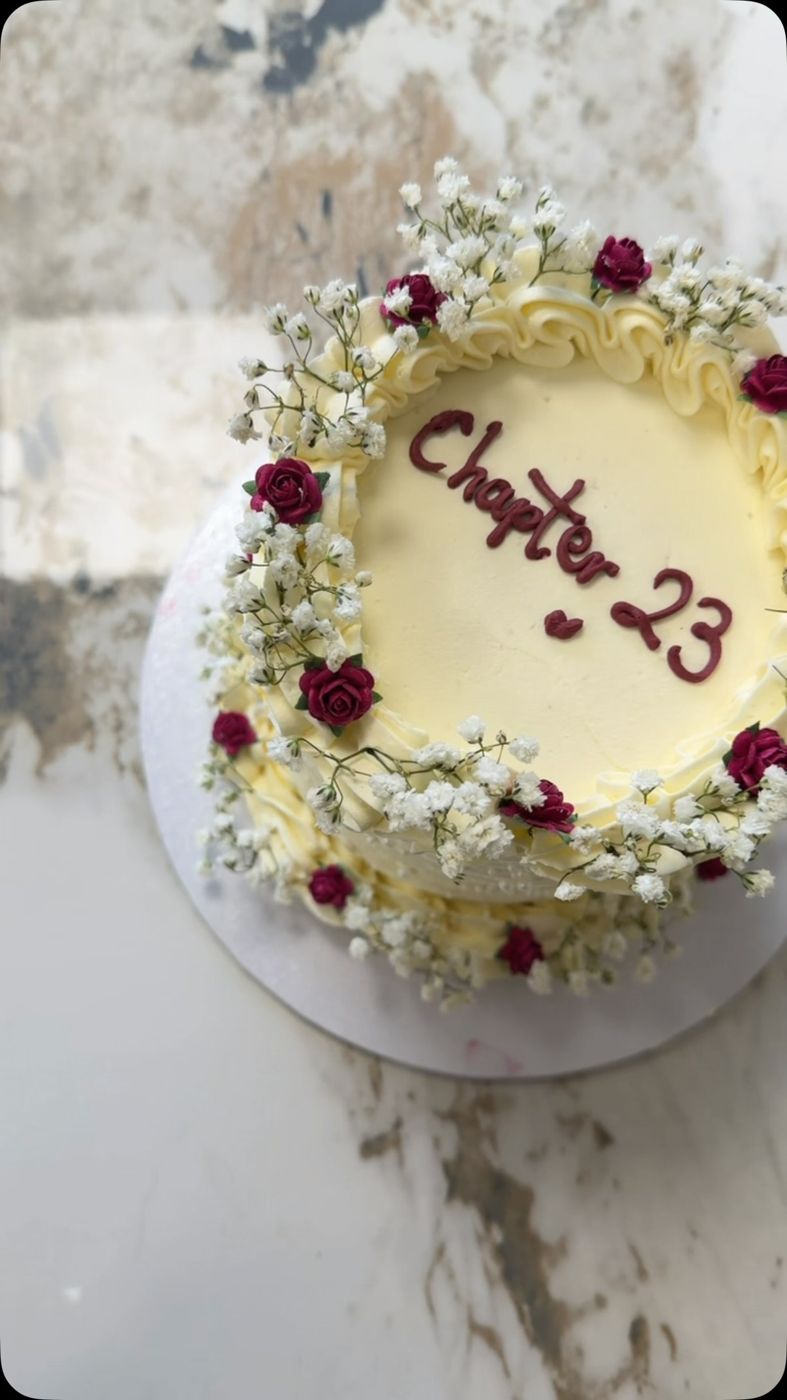 A custom cream cake with berries and piped lettering